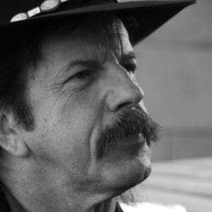 Black and white portrait of a man with a mustache wearing a hat.